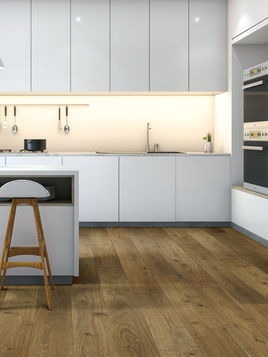 A kitchen with white cabinets and countertops and wood floors.